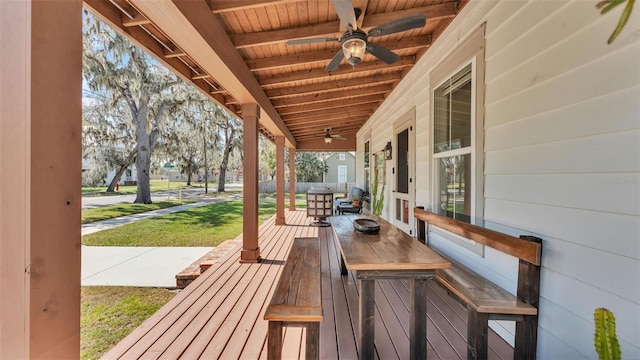 wooden deck featuring covered porch, a lawn, and a ceiling fan