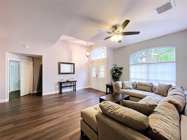 living room featuring dark wood-style flooring, baseboards, a textured ceiling, visible vents, and ceiling fan