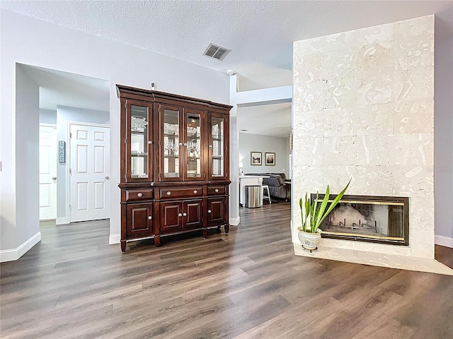 interior space featuring a textured ceiling, wood finished floors, baseboards, and visible vents