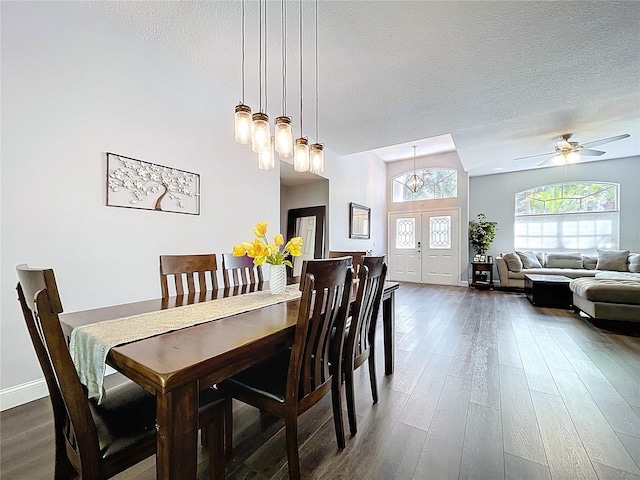 dining room with dark wood-style floors, a textured ceiling, baseboards, and a ceiling fan