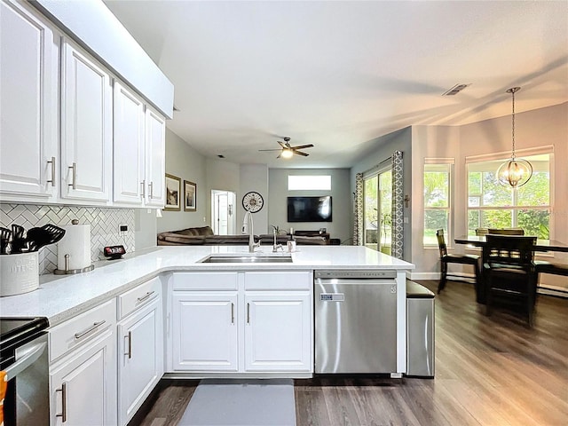 kitchen with a peninsula, stainless steel dishwasher, a sink, and white cabinetry