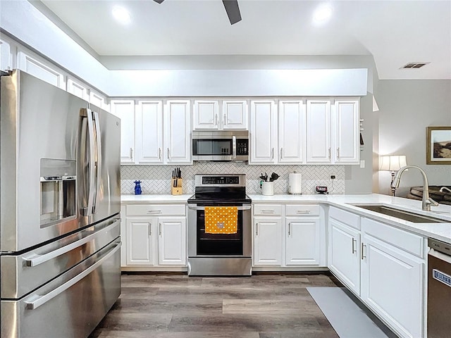 kitchen featuring dark wood-style floors, white cabinetry, visible vents, stainless steel appliances, and a sink