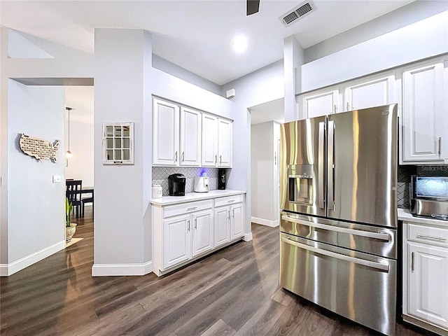 kitchen with white cabinets, visible vents, light countertops, stainless steel fridge, and backsplash