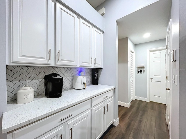 kitchen with tasteful backsplash, white cabinets, baseboards, dark wood-style floors, and light stone counters