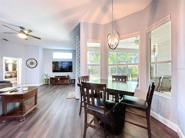 dining area featuring a textured ceiling, ceiling fan with notable chandelier, baseboards, and dark wood-style floors