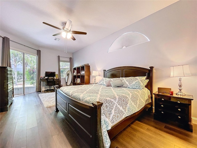 bedroom featuring access to outside, hardwood / wood-style floors, a ceiling fan, and visible vents