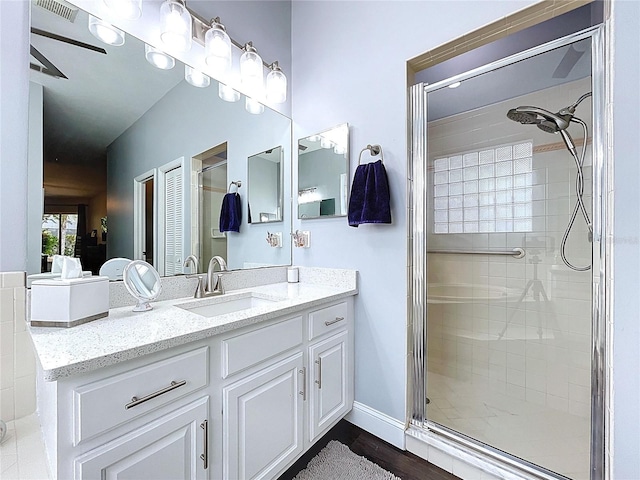 bathroom with visible vents, baseboards, a shower stall, and vanity