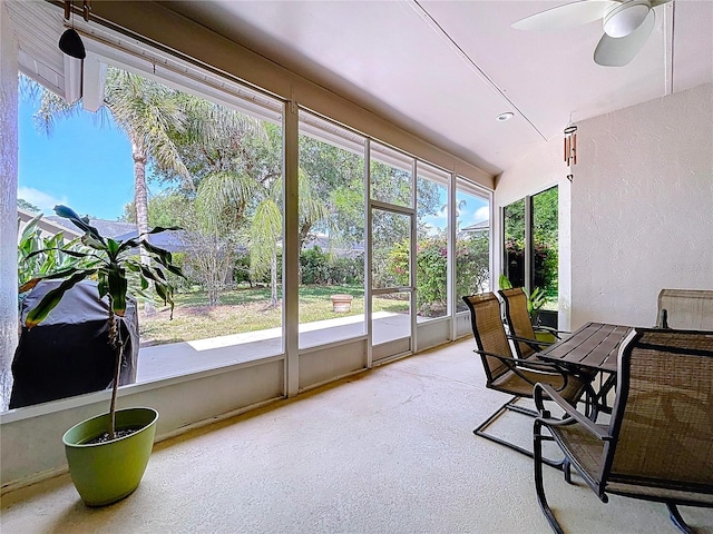 sunroom with outdoor dining area and a ceiling fan