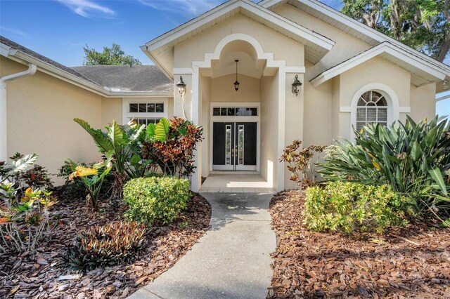6928 Hayter Ln, Lakeland, FL 33813 - property entrance with french doors, roof with shingles, and stucco siding