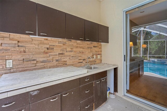 6928 Hayter Ln, Lakeland, FL 33813 - kitchen with a sink, tasteful backsplash, dark brown cabinetry, unfinished concrete flooring, and light countertops