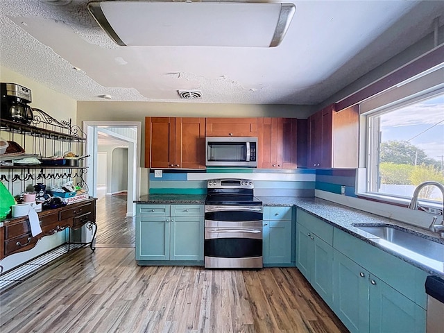 105 Old Connersville Rd, Bartow, FL 33830 - kitchen with appliances with stainless steel finishes, a sink, light wood-style floors, a textured ceiling, and arched walkways