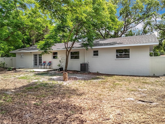 back of house featuring central air condition unit, a shingled roof, fence, french doors, and a patio