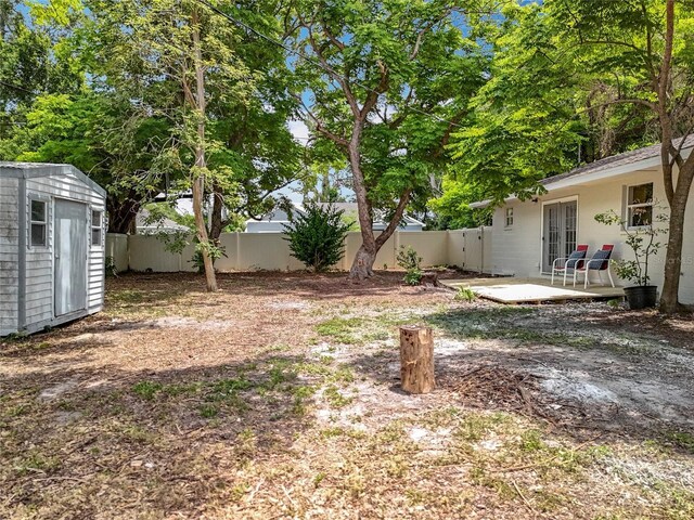 fenced backyard with an outbuilding, a storage shed, and a patio