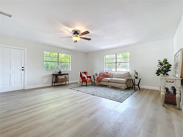 living room with plenty of natural light, light wood finished floors, ceiling fan, and baseboards