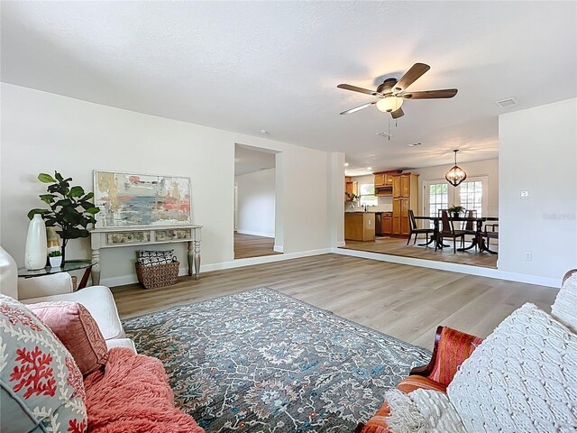 living room with ceiling fan, light wood-style flooring, and baseboards