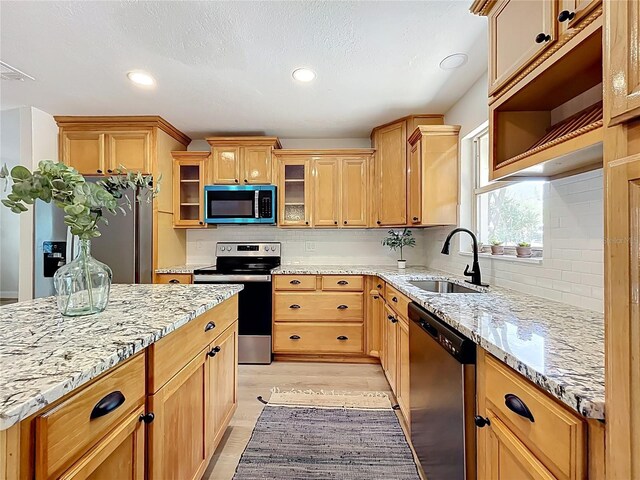 kitchen with appliances with stainless steel finishes, a sink, light wood-style floors, backsplash, and recessed lighting