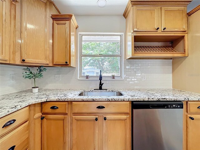 kitchen with stainless steel dishwasher, a sink, backsplash, and light stone countertops