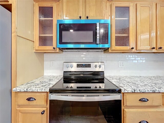 kitchen featuring stainless steel appliances, backsplash, glass insert cabinets, and light stone counters