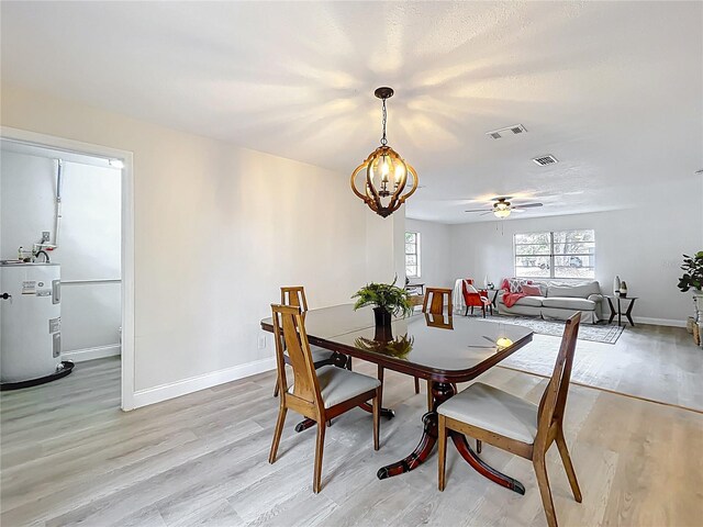 dining space with water heater, a chandelier, light wood-type flooring, baseboards, and a ceiling fan