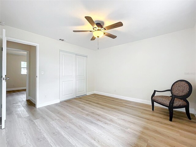 unfurnished bedroom featuring light wood finished floors, baseboards, a closet, and a ceiling fan