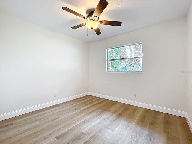 spare room with baseboards, light wood-type flooring, and ceiling fan