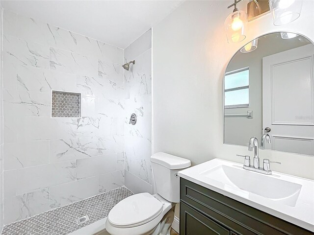 bathroom featuring toilet, a tile shower, and vanity