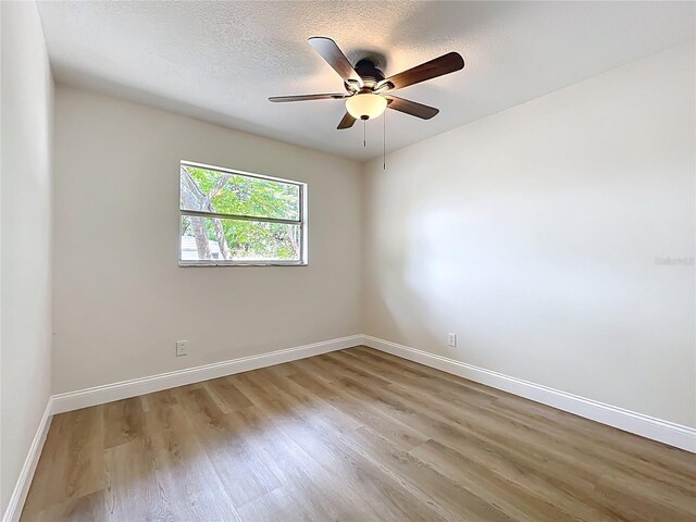unfurnished room featuring light wood finished floors, baseboards, ceiling fan, and a textured ceiling