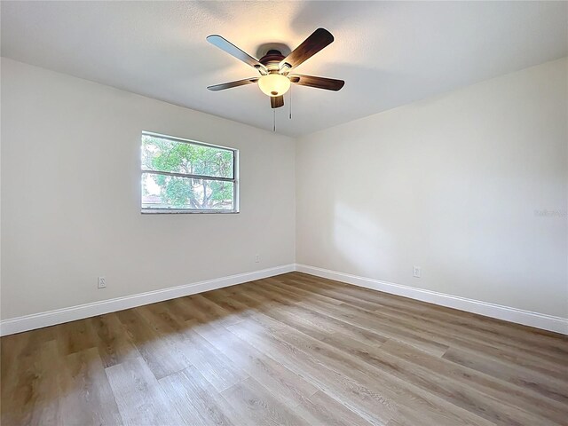 empty room with wood finished floors, baseboards, and ceiling fan