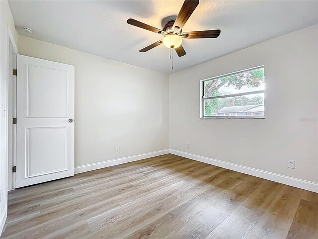 unfurnished room featuring a ceiling fan, light wood finished floors, baseboards, and a smoke detector