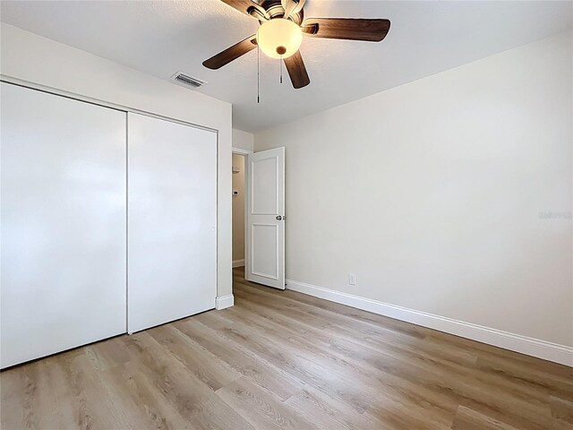 unfurnished bedroom with light wood-style floors, a closet, baseboards, and ceiling fan
