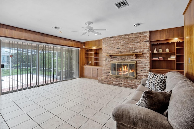 900 Howard Ter NW, Winter Haven, FL 33881 - living room featuring light tile patterned floors, ceiling fan, built in shelves, a fireplace, and wood walls