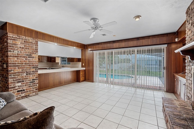 900 Howard Ter NW, Winter Haven, FL 33881 - unfurnished living room featuring wooden walls, a ceiling fan, light tile patterned floors, and a sink