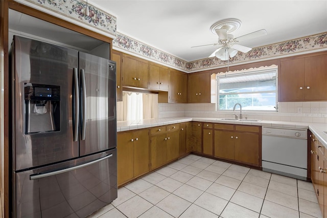 900 Howard Ter NW, Winter Haven, FL 33881 - kitchen featuring stainless steel fridge with ice dispenser, dishwasher, a sink, brown cabinetry, and a ceiling fan
