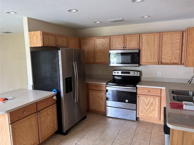 340 W Stanford St, Bartow, FL 33830 - kitchen featuring stainless steel appliances, a sink, light tile patterned floors, a textured ceiling, and light countertops