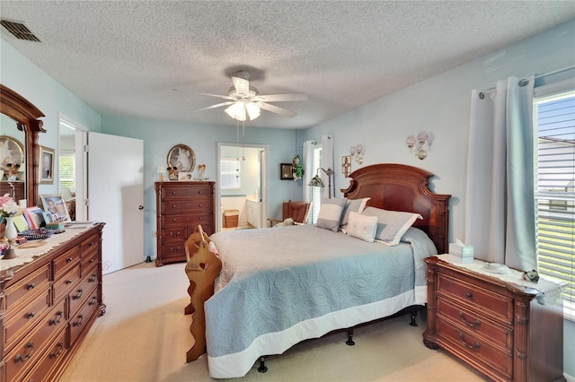 3154 Prairie Dunes Cir W, Lakeland, FL 33810 - bedroom with light carpet, a textured ceiling, a ceiling fan, and connected bathroom