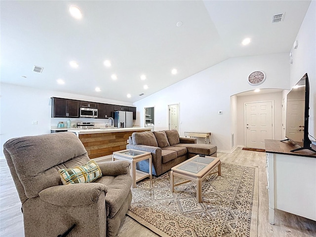 1205 Third Ct, Eagle Lake, FL 33839 - living room featuring arched walkways, light wood finished floors, high vaulted ceiling, and recessed lighting