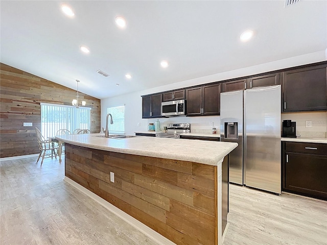 1205 Third Ct, Eagle Lake, FL 33839 - kitchen featuring stainless steel appliances, wood walls, vaulted ceiling, light wood-style flooring, and an island with sink
