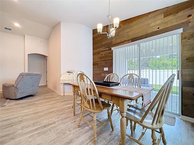 1205 Third Ct, Eagle Lake, FL 33839 - dining room featuring wooden walls, arched walkways, light wood-style flooring, a chandelier, and lofted ceiling