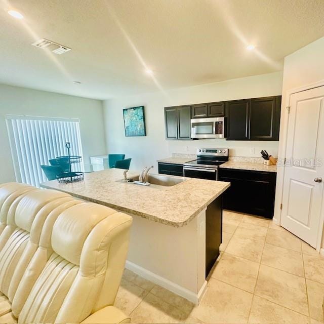264 Fiddlewood Ct, Davenport, FL 33837 - kitchen with stainless steel appliances, dark cabinetry, open floor plan, light tile patterned floors, and light countertops