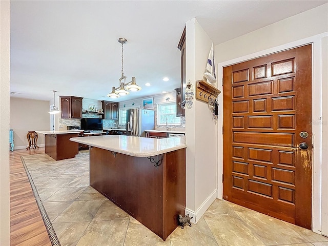 4966 Foxrun Ln, Lakeland, FL 33813 - kitchen with stainless steel refrigerator with ice dispenser, a peninsula, light countertops, a kitchen bar, and recessed lighting