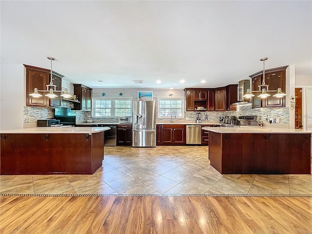 4966 Foxrun Ln, Lakeland, FL 33813 - kitchen featuring stainless steel appliances, wall chimney range hood, a peninsula, tasteful backsplash, and light countertops
