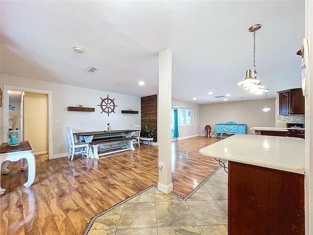 4966 Foxrun Ln, Lakeland, FL 33813 - kitchen with light countertops, dark brown cabinetry, open floor plan, light wood-type flooring, and pendant lighting