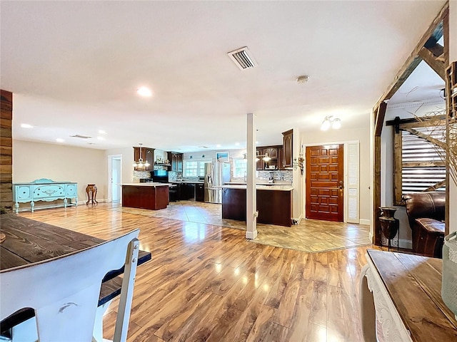 4966 Foxrun Ln, Lakeland, FL 33813 - kitchen featuring dark brown cabinets, light wood-type flooring, light countertops, stainless steel fridge with ice dispenser, and open floor plan