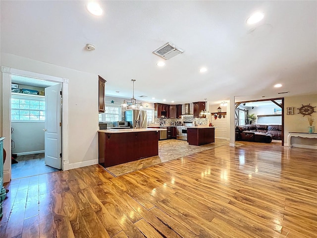 4966 Foxrun Ln, Lakeland, FL 33813 - kitchen with open floor plan, stainless steel appliances, a peninsula, light wood-style flooring, and light countertops