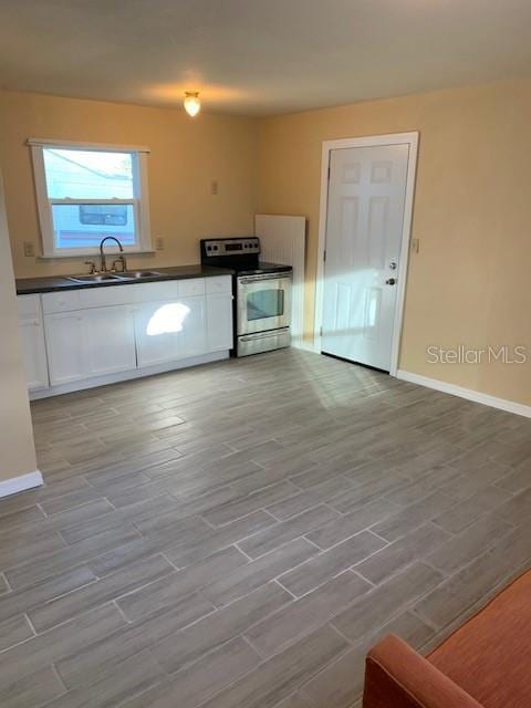 402 S Franklin St, Sebring, FL 33870 - kitchen featuring stainless steel electric range, dark countertops, white cabinetry, and wood finished floors