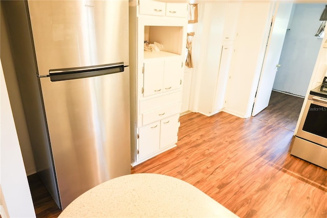 733 Oleander Dr SE, Winter Haven, FL 33880 - kitchen with freestanding refrigerator, white cabinets, light wood-type flooring, and white electric stove