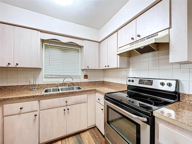 1711 Estes Rd, Bartow, FL 33830 - kitchen featuring stainless steel range with electric cooktop, under cabinet range hood, light wood finished floors, backsplash, and light countertops