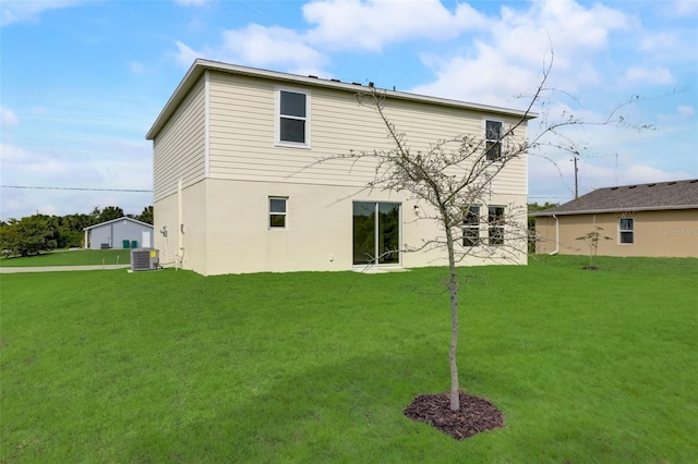 rear view of property featuring central AC unit and a lawn