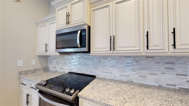 kitchen featuring tasteful backsplash, white cabinetry, electric range, and light stone counters