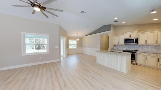 kitchen with light wood-type flooring, light stone countertops, and appliances with stainless steel finishes